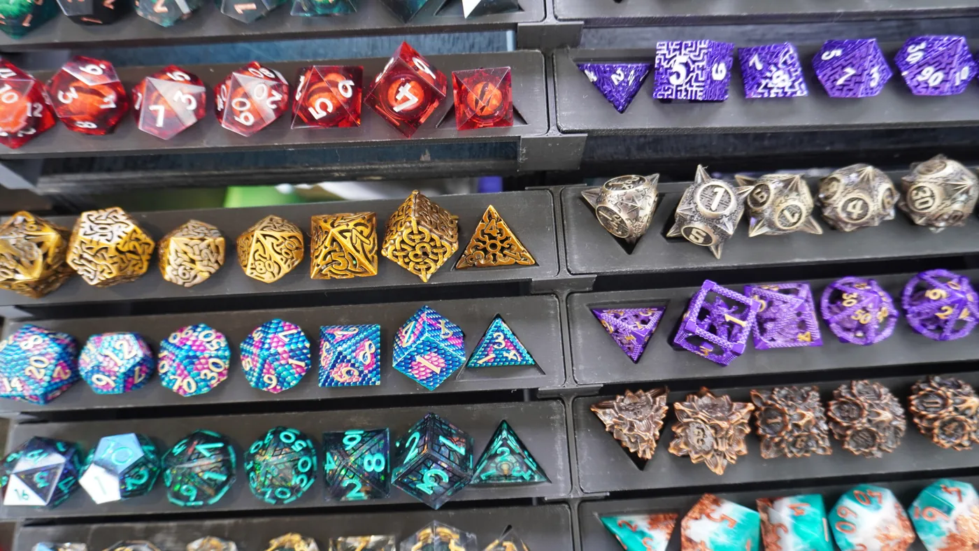 Close-up of vendor display trays holding red, gold, purple and teal metal dice sets