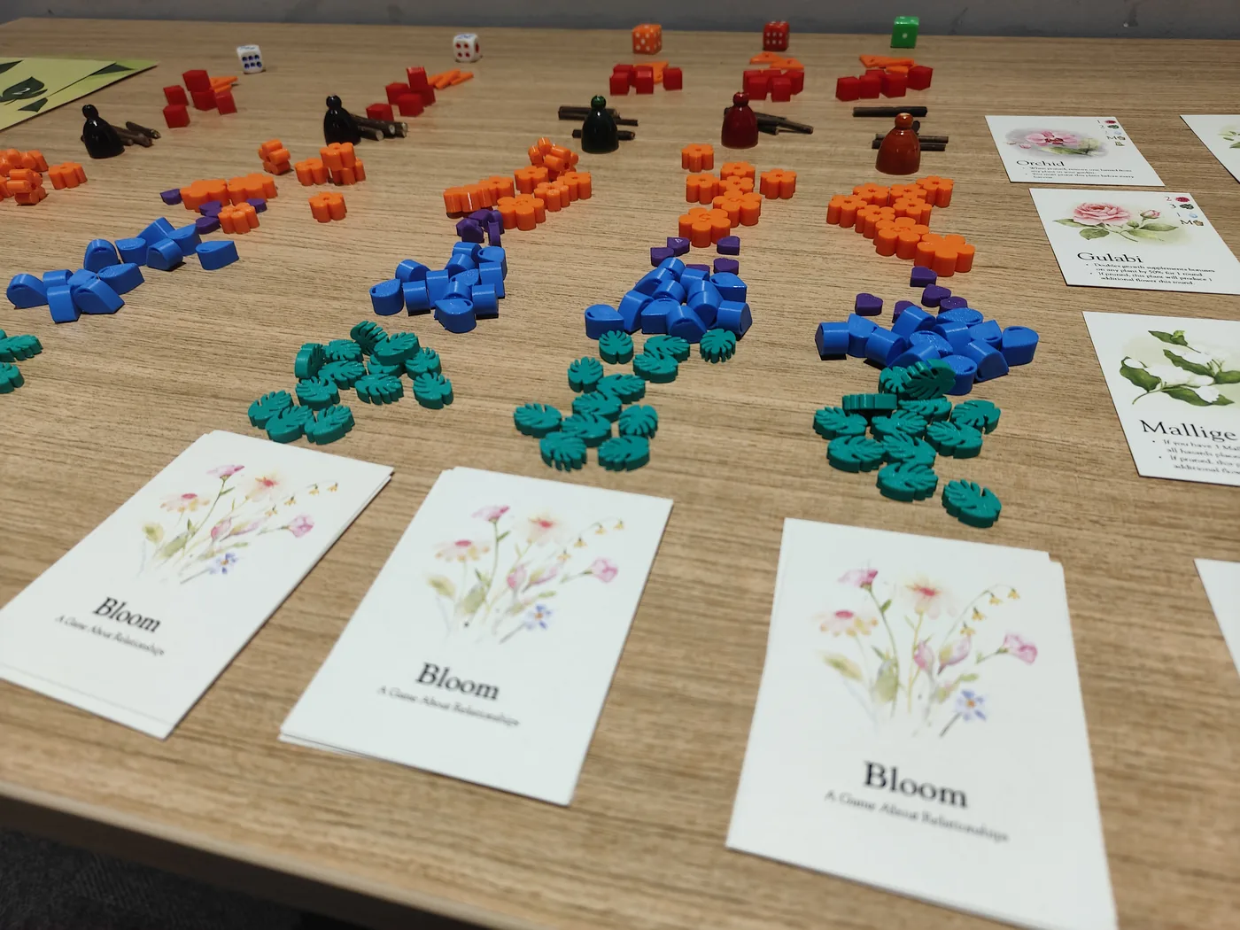 Bloom game pieces and flower cards laid out across a workshop table