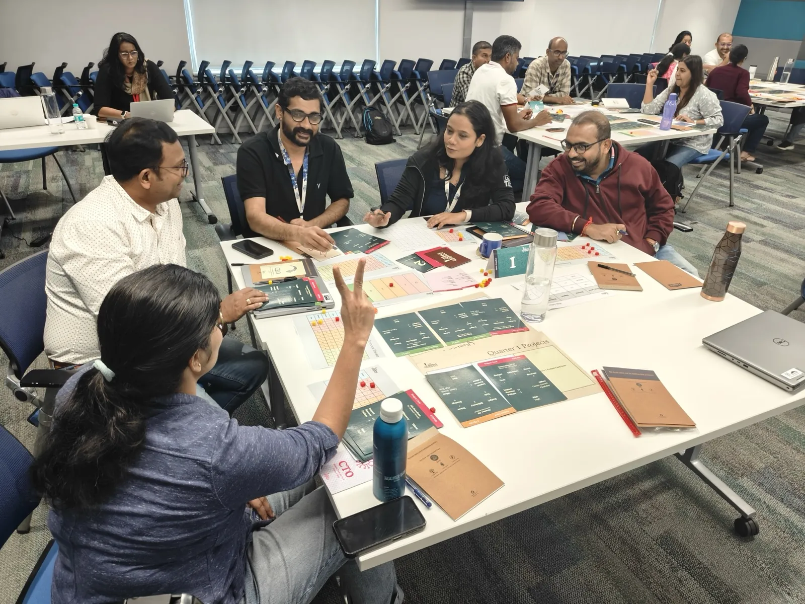 Teams playing a business strategy game across several tables in a leadership workshop