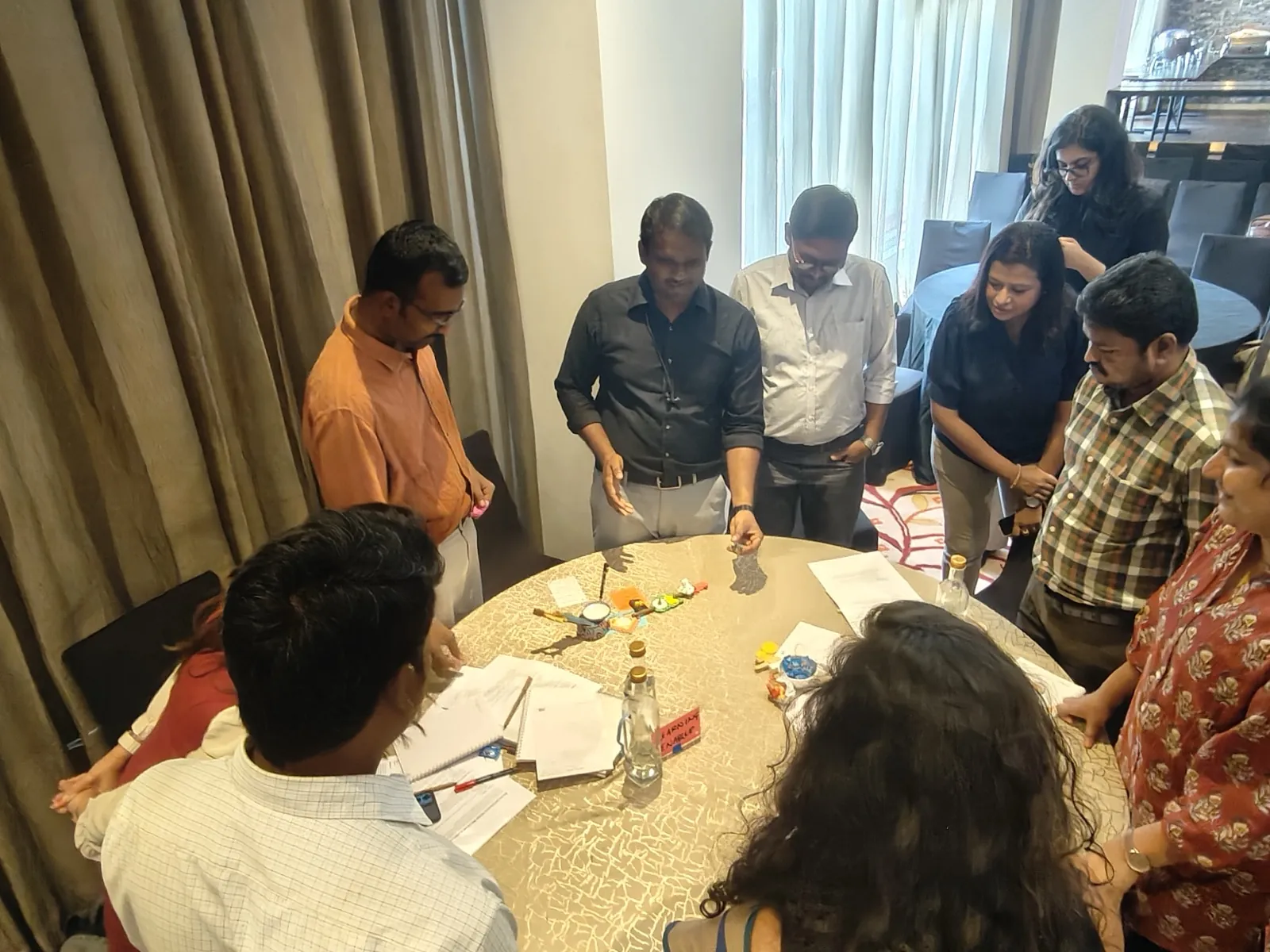 Team collaborating around a round workshop table with game materials