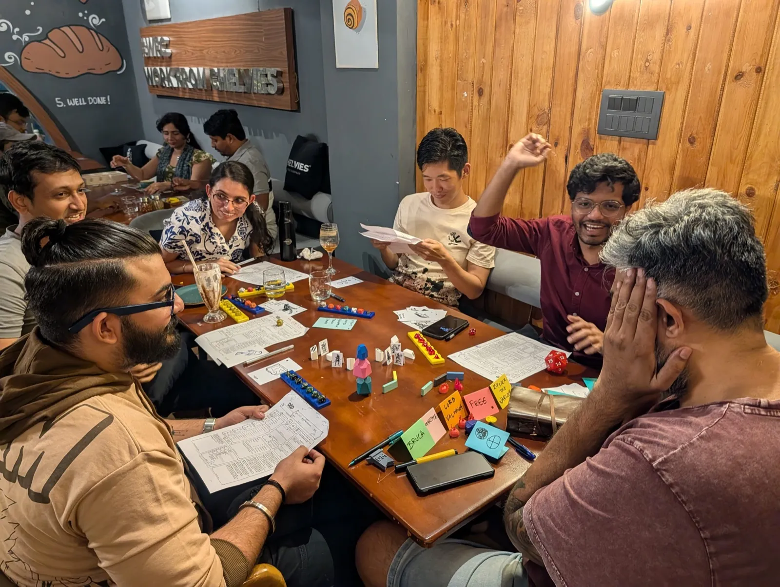Team deeply engaged in a tabletop workshop game around a wooden table